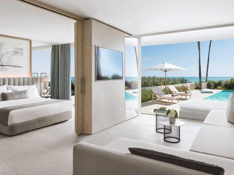 Helles Zimmer mit Doppelbett, Sofa, TV, Zugang zur Terrasse mit Pool und Meerblick.