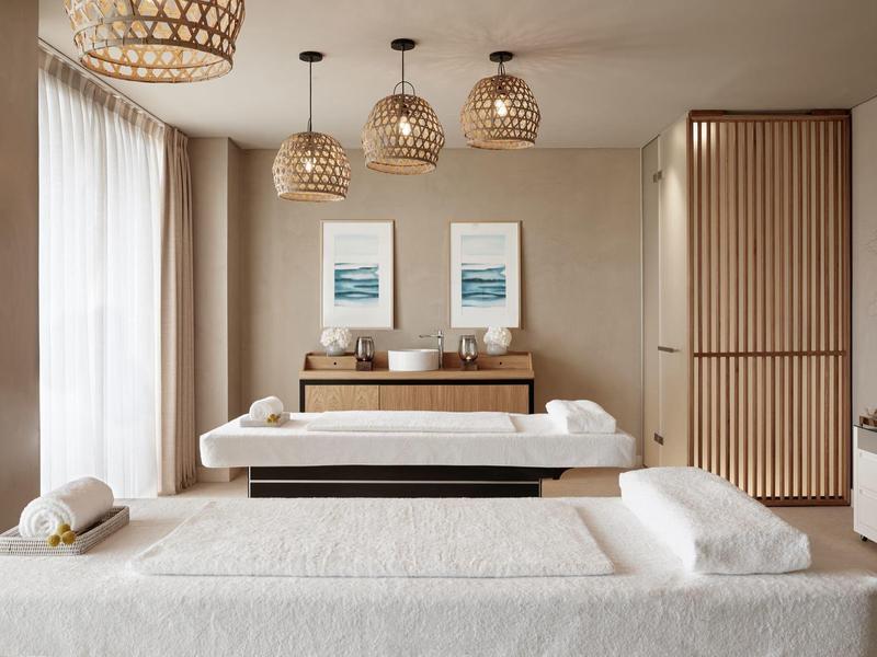 Helles, modernes Wellnesszimmer mit Massagebank, Bett, sanfter Beleuchtung und natürlichen Holzelementen.