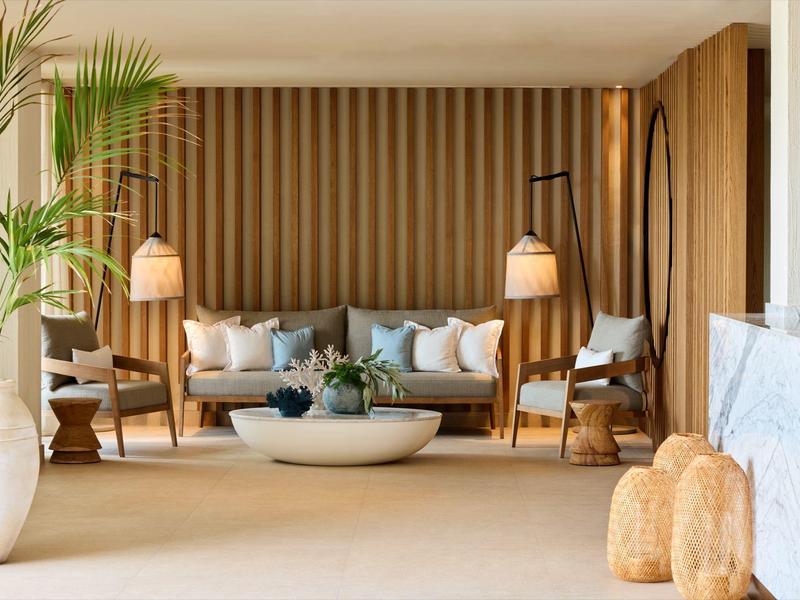 Modernes Wohnzimmer mit Holzvertäfelung, Sofas, runden Lampen und großen Pflanzen in heller Einrichtung.