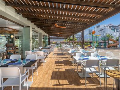 Freiluft-Terrasse mit weißem Mobiliar, Holzboden und Holzdach in modernem Restaurant.