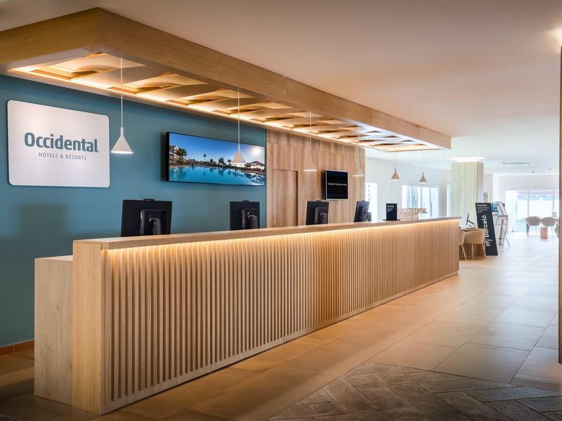 Moderner Empfangsbereich mit hellen Holzelementen, blauem Wandakzent und indirekter Beleuchtung.