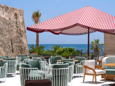 Freiluftterrasse mit modernen Sitzmöbeln und Sonnenschirmen mit Blick aufs Meer.