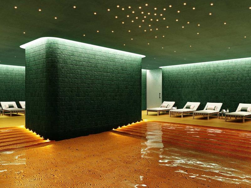 Moderner Indoor-Pool mit grünen Wänden, beleuchtetem Sternenhimmel und weißen Liegen am Rand.