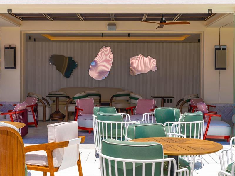 Offener Sitzbereich mit bunten Stühlen, Tischen und moderner Wanddekoration in warmem Licht.