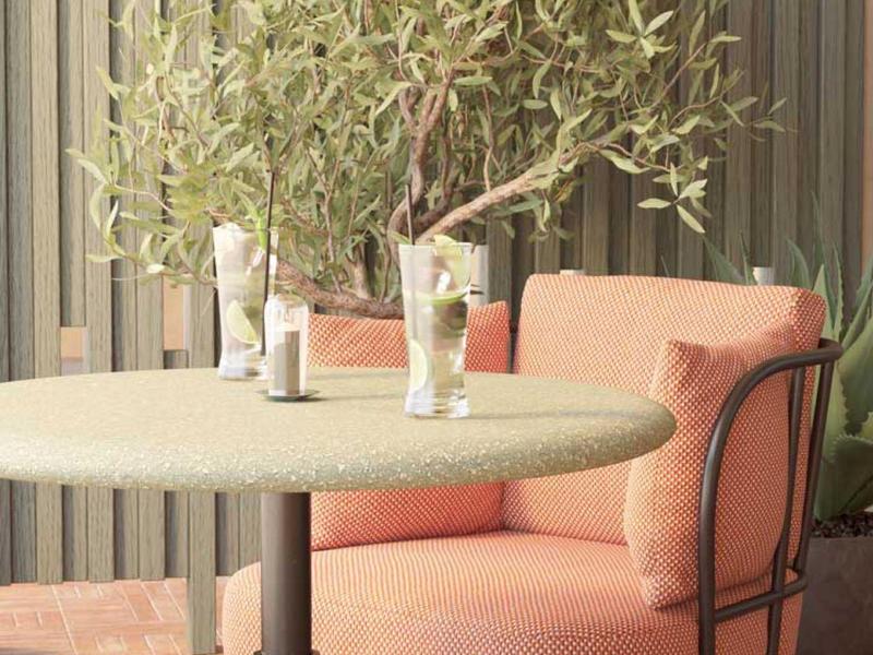 Moderner Sitzbereich mit rundem Tisch, zwei Gläsern Wasser und einem grünen Pflanzenzweig.