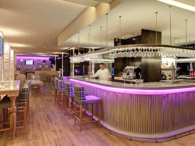 Moderne Hotelbar mit beleuchtetem Tresen, Holzfußboden und gemütlichen Hockern