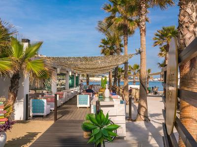 Moderner Hotelstrand mit Palmen, komfortablen Sitzgelegenheiten und Blick auf das Meer bei sonnigem Wetter