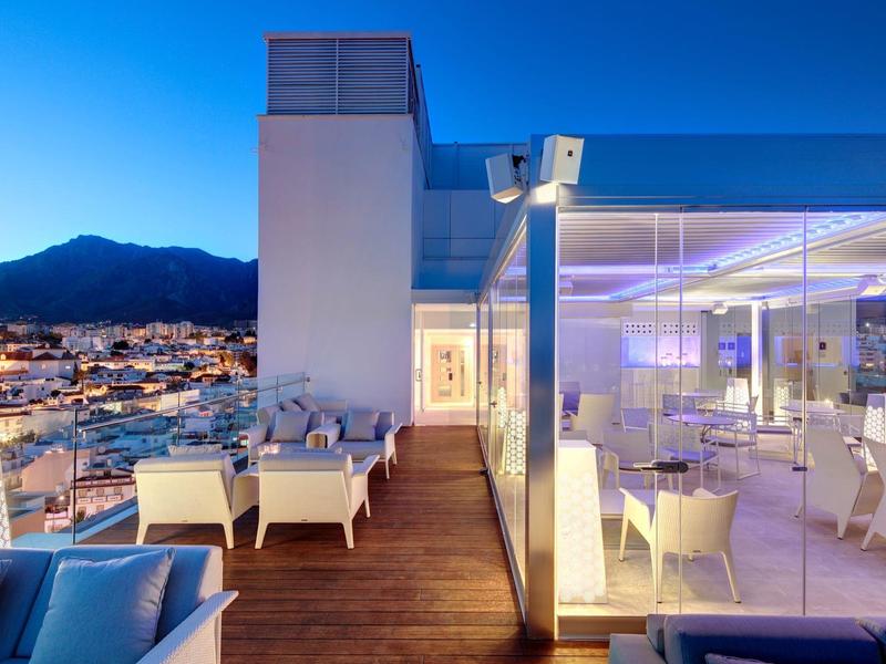 Moderne Dachterrasse mit Sitzbereich und Restaurant bei Dämmerung mit Bergblick.