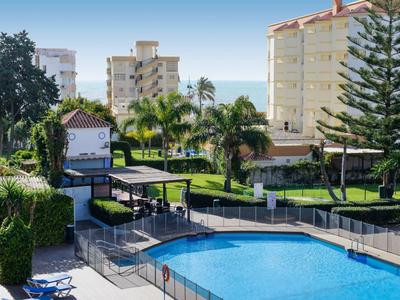 Außenpool mit Liegestühlen und umgeben von palmen und mehrstöckigen Gebäuden.