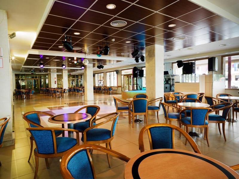 Geräumiger Saal mit runden Tischen und blauen Stühlen in einem Restaurant oder Hotel.