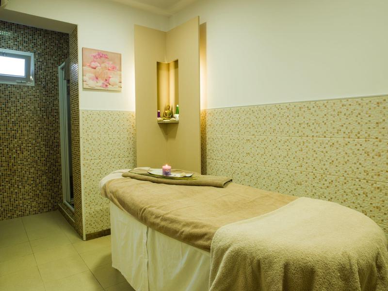 Gemütlicher Massagetisch in einem ruhigen, hellen Wellnessraum mit weichen Handtüchern.