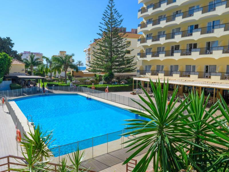 Außenpool neben einem mehrstöckigen Hotelgebäude mit angrenzenden Pflanzen