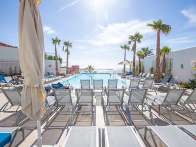 Moderner Poolbereich mit Liegestühlen, Sonnenschirmen und Palmen unter klarem, blauem Himmel.