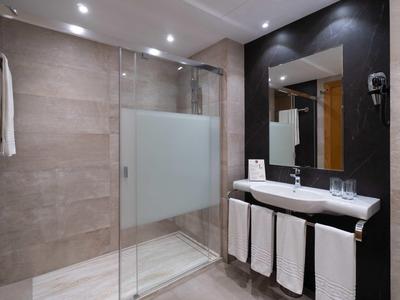 Modernes Badezimmer mit Glastür-Dusche, großem Spiegel und weißem Waschbecken mit Handtüchern.