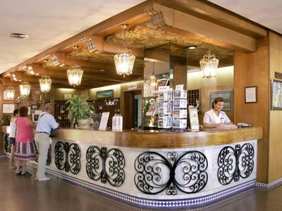 Hotelrezeption mit hölzerthematischer Theke, dekorativen Leuchten und mehreren wartenden Gästen.