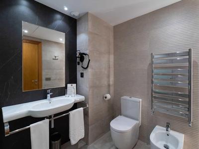 Modernes Badezimmer mit weißem Waschbecken, Toilette, Bidet und silbernem Handtuchwärmer.