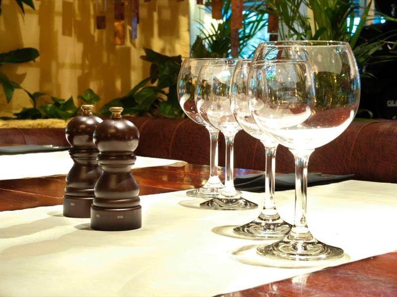 Vier leere Weingläser und zwei schwarze Pfeffer- und Salzmühlen auf gedecktem Tisch.