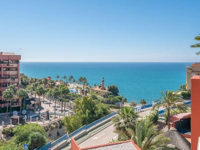 Blick auf eine Küstenstadt mit Meer, Palmen und Gebäuden bei klarem Himmel.
