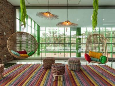 Dunkler Raum mit blauer Beleuchtung, zwei Personen an PCs mit Spiele-Setup und Neon-Gaming-Zeichen.