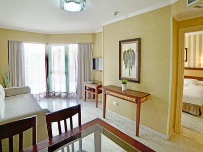 Gemütliches Hotelzimmer mit Sitzecke, Tisch und separatem Schlafzimmer mit Doppelbett.