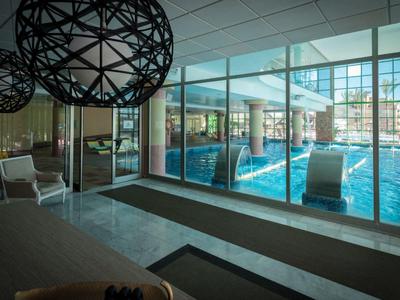 Moderner Innenpoolbereich mit großen Fenstern und gemütlichen Sitzmöglichkeiten.