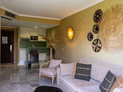 Gemütlicher Hotel-Loungeraum mit Sofa, Kissen und dekorativen Wandobjekten in warmen Farben.