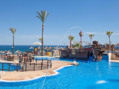 Großer Außenpool mit Palmen und Meerblick an sonnigem Tag