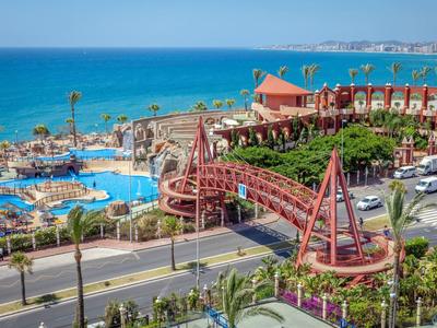 Blick auf ein Hotelresort mit Pool, Straßenbahn und Meer im Hintergrund.