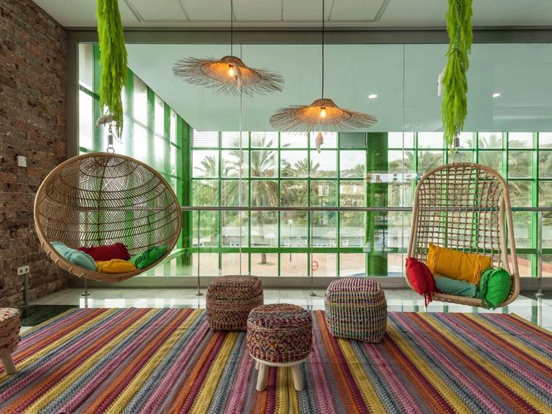 Dunkler Raum mit blauer Beleuchtung, zwei Personen an PCs mit Spiele-Setup und Neon-Gaming-Zeichen.