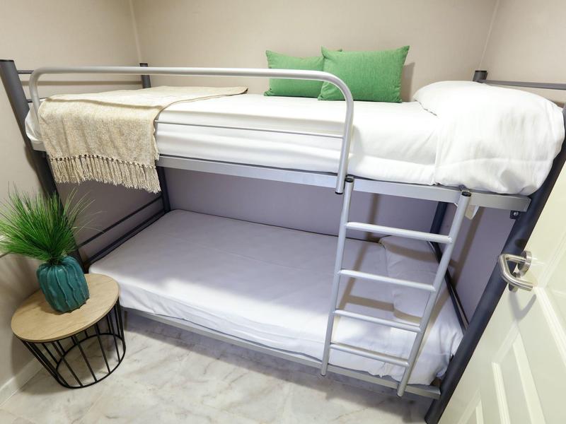 Modernes Etagenbett mit weißen Bettwäsche und grünem Kissen in hellem Raum.