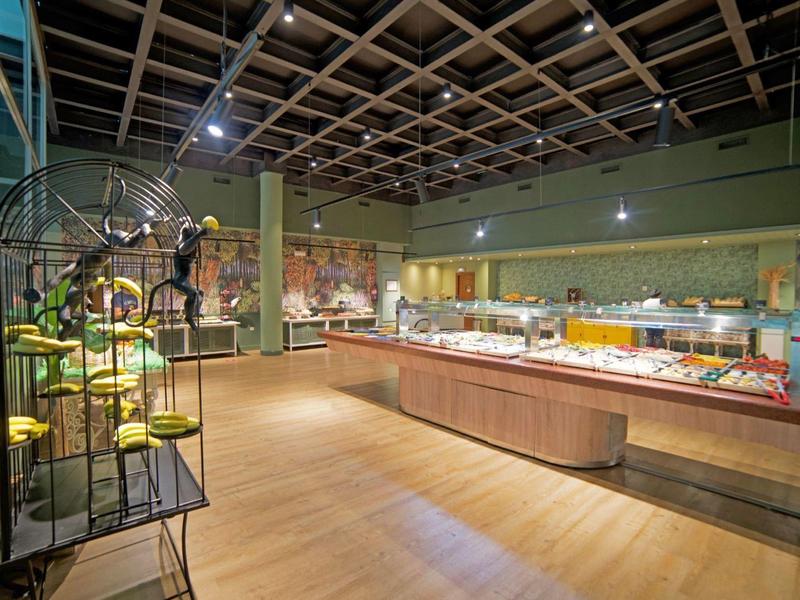 Ein großzügiger Buffetsaal mit verschiedenen Speisen auf langen Tischen und modernen Deckenlampen.