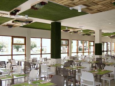 Helles, modernes Restaurant mit weißen und grauen Stühlen und grünen Tischsets.