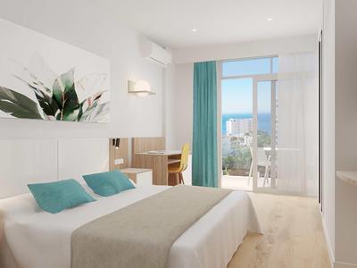 Minimalistisches Schlafzimmer mit Doppelbett, türkisen Kissen, Holzfußboden und Balkon mit Meerblick.