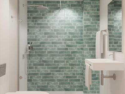 Modernes Badezimmer mit grüner Mosaikfliesen-Dusche, weißer Toilette und kleinem Waschbecken.