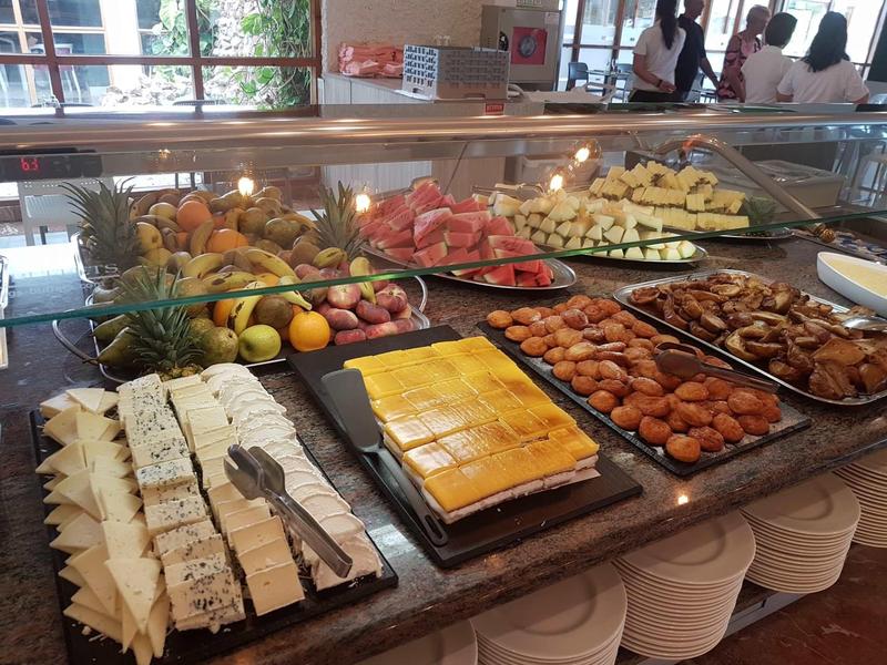 Buffet mit verschiedenen Käsesorten, Früchten, Kuchen und Gebäck auf gedecktem Tisch.