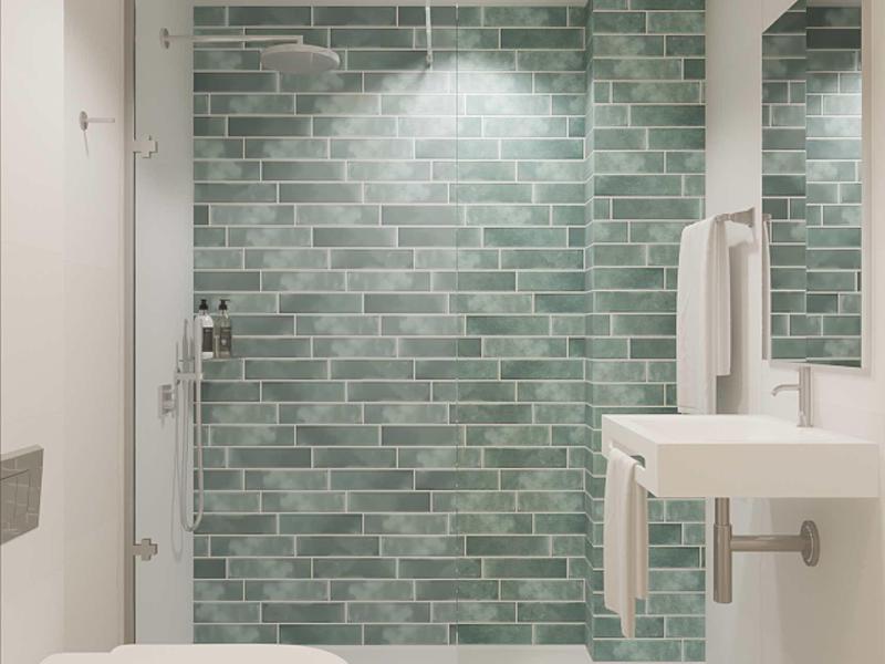 Modernes Badezimmer mit grüner Mosaikfliesen-Dusche, weißer Toilette und kleinem Waschbecken.