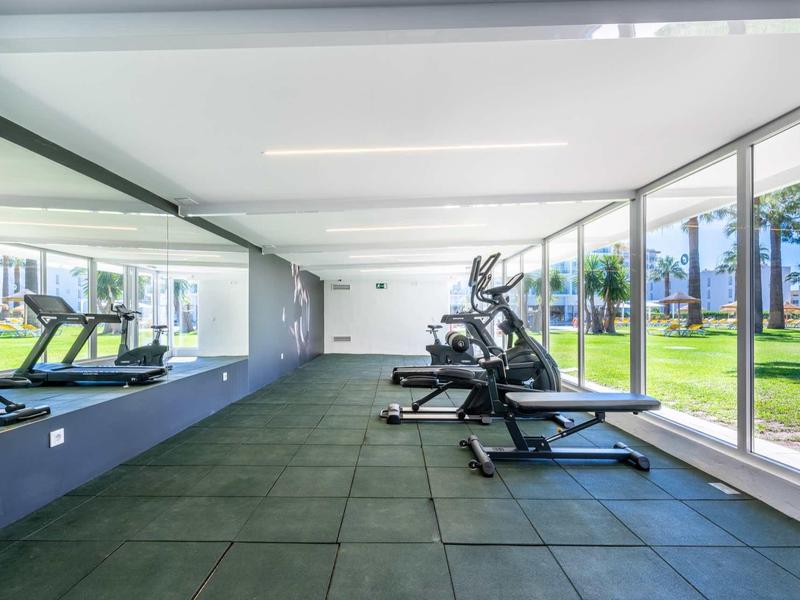 Moderner Fitnessraum mit Laufbändern, großen Fenstern und grüner Außenansicht.