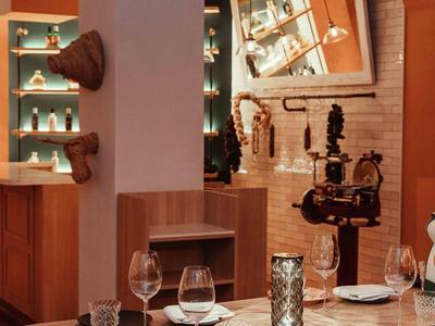 Ristorante moderno con tavolo in legno, stoviglie apparecchiate e atmosfera calda arancione.