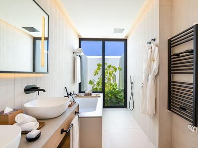 Helle, moderne Badezimmereinrichtung mit großer Glasfront, Holzablage und weißen Sanitäranlagen.