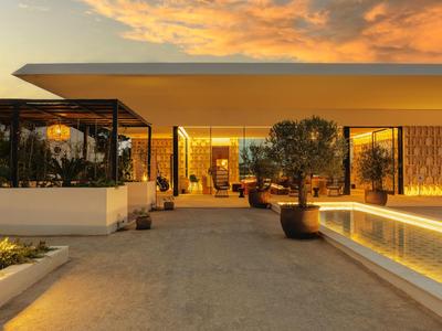 Area moderna dell'hotel al tramonto con illuminazione e piante.