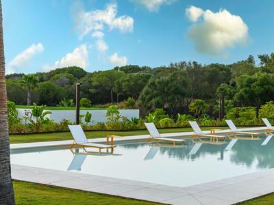 Area piscina esterna moderna con lettini e paesaggio verde sullo sfondo