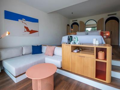 Helles Wohnzimmer mit hellgrauem Sofa, bunter Deko, Holzregal und modernem Wandbild.