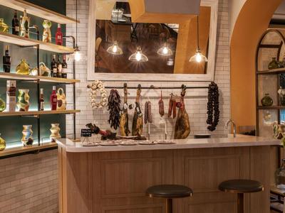 Gemütliche Bar mit Holztheke, zwei Hockern, Wurst-Deko und warmem Beleuchtungskonzept.