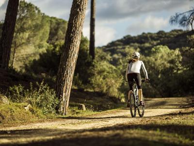 Persona in mountain bike su un sentiero boschivo con il sole.