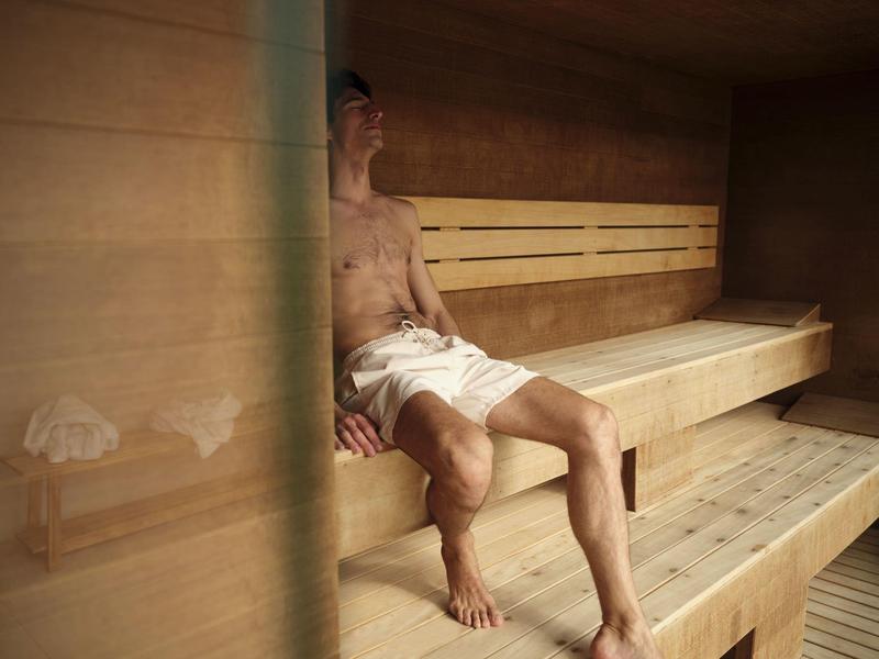 Moderner Pool mit weißen Liegestühlen, Palmen und grünem Hintergrund unter blauem Himmel.