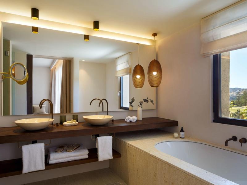 Moderne Badezimmer mit Doppelwaschbecken, großem Spiegel, Badewanne und warmem Licht in neutralen Tönen.
