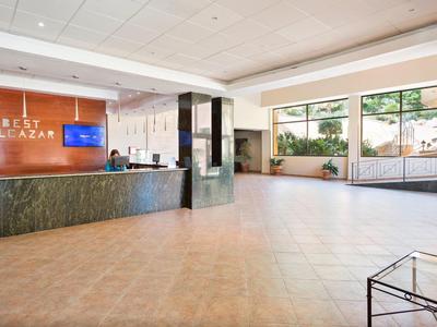 Hell gestalteter Empfangsbereich mit großem Tresen, Sitzgelegenheit und großen Fenstern.