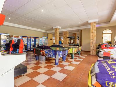 Recreation room with pool tables, arcade games, and seating in a hotel.