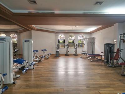 Bright, spacious gym with wooden flooring and various workout machines.