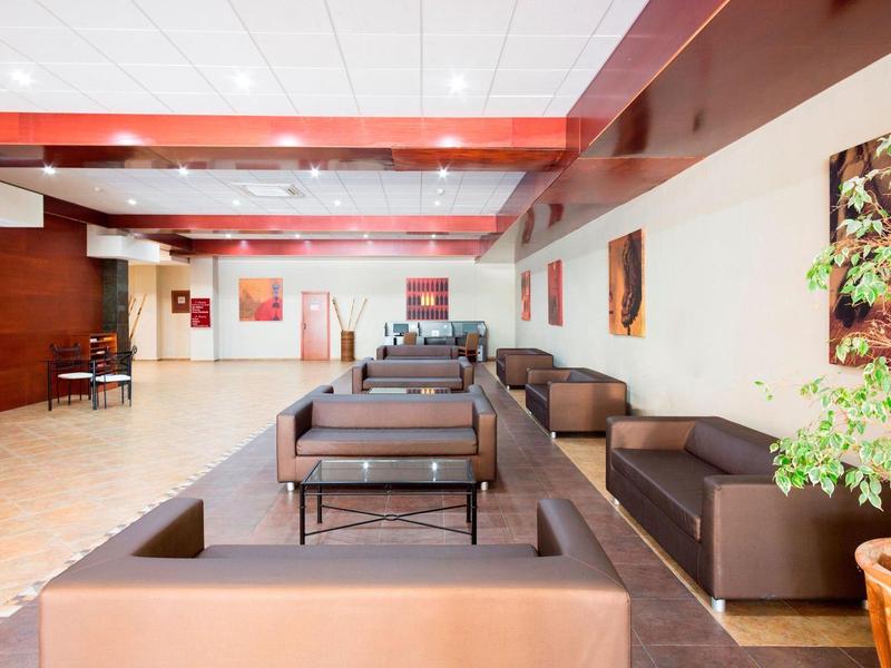 Großer, heller Raum mit braunen Ledersofas, bunten Bildern an weißen Wänden und Pflanzen im Topf.